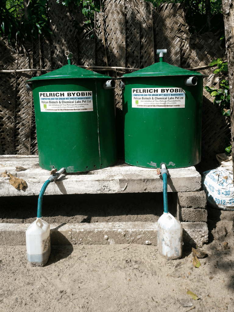 Two green waste management bins labeled "Pelrich Byobin" with hoses leading to containers on a concrete platform.